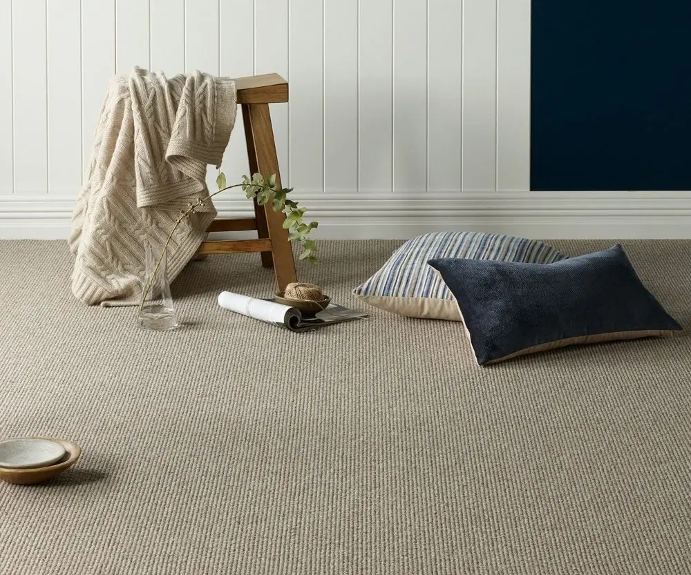 Light grey textured carpet in a bright boho living room with rattan furniture, Carpets Dubai.